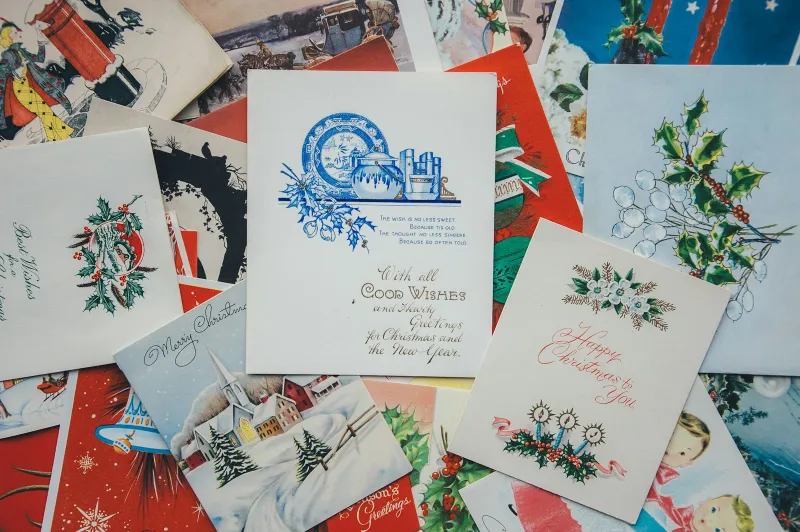 A pile of colourful vintage Christmas and greeting cards spread across a table