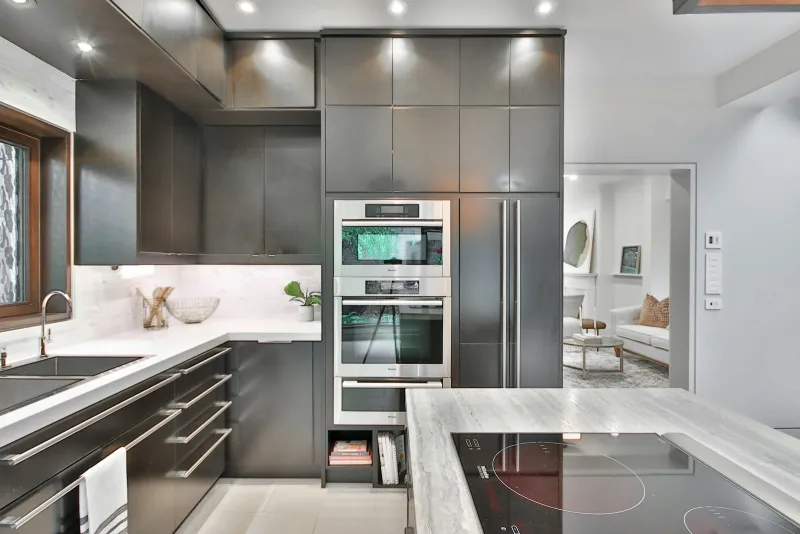 A modern grey kitchen with built-in stainless steel ovens and an induction hob