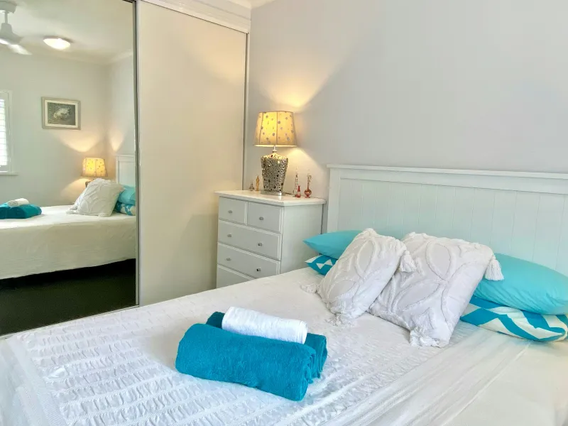 White wooden bed frame made up with white pillows