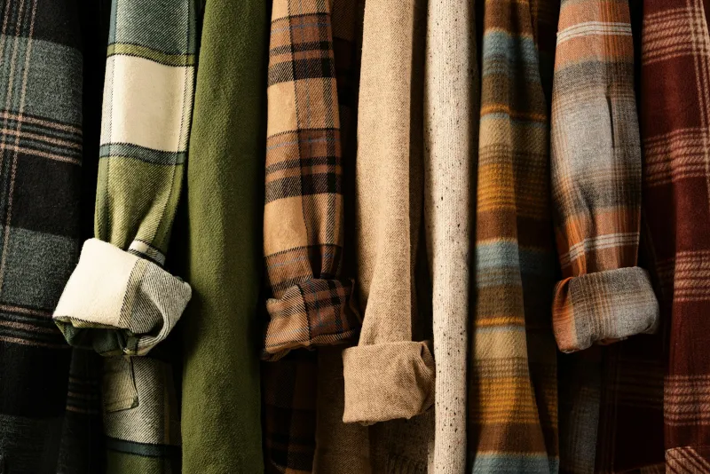 Plaid flannel shirts and knitwear hanging side by side on a rail