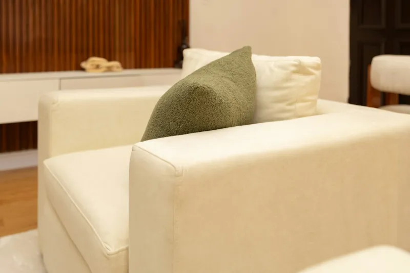 Cream upholstered armchair with a green cushion