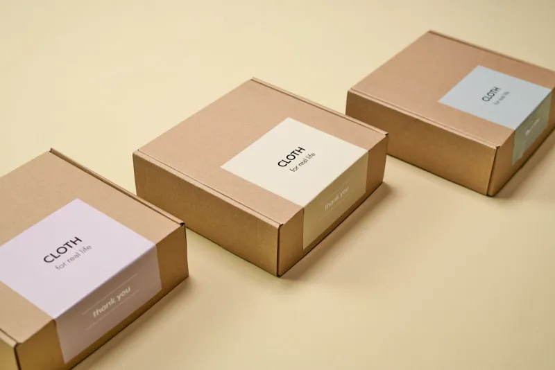 Three brown cardboard parcels lined up on a pale yellow surface