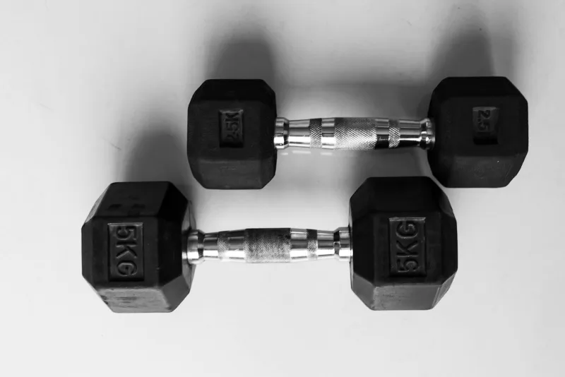 Two pairs of black hexagonal dumbbells on a pale background