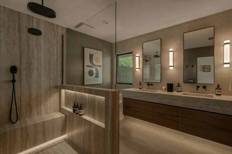 Modern bathroom with a glass walk-in shower, stone walls and a double vanity
