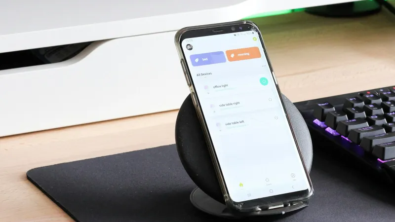 Smartphone in a clear case resting on a wireless charging stand beside a keyboard