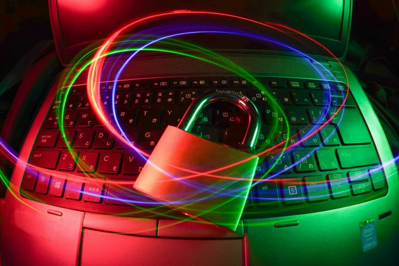 A padlock resting on a laptop keyboard, circled by coloured light trails