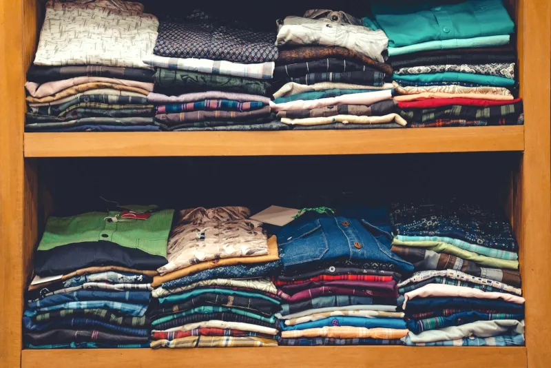 Wooden shelves stacked with folded shirts in checks, prints and plain colours
