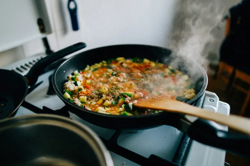 Field Doctor: chef-made frozen meals from Somerset, delivered Pan of vegetable rice cooking on a hob with a wooden spoon