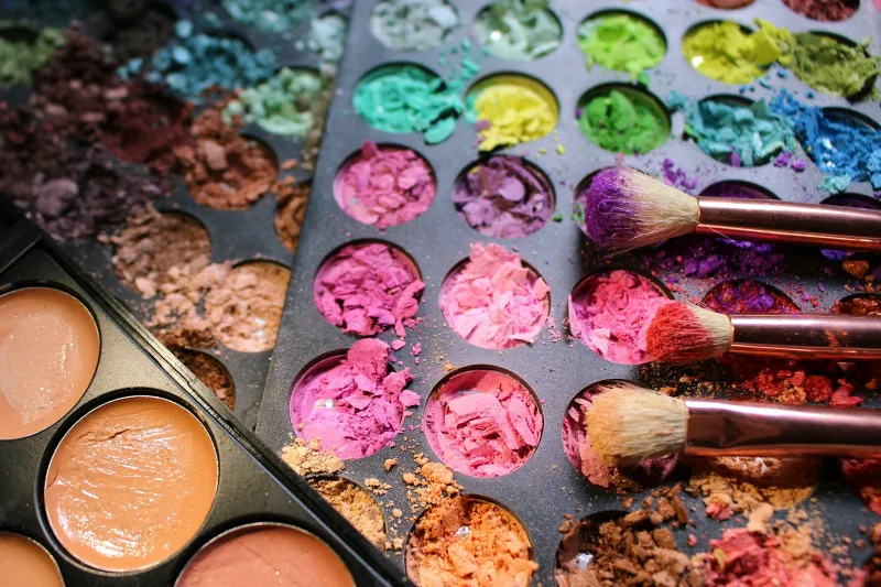 Close-up of colourful crushed eyeshadow palettes with make-up brushes