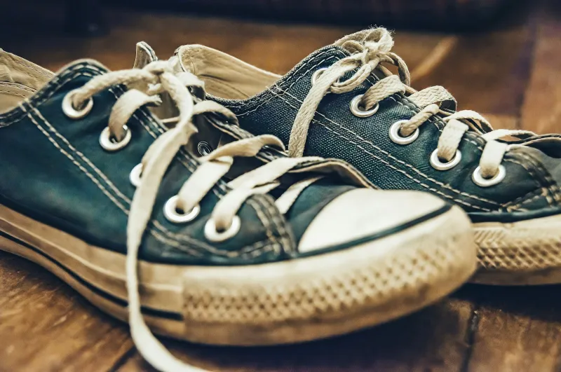 Worn pair of canvas trainers on a wooden floor