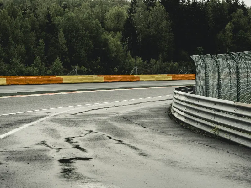 An empty motor racing circuit corner with barriers and trees
