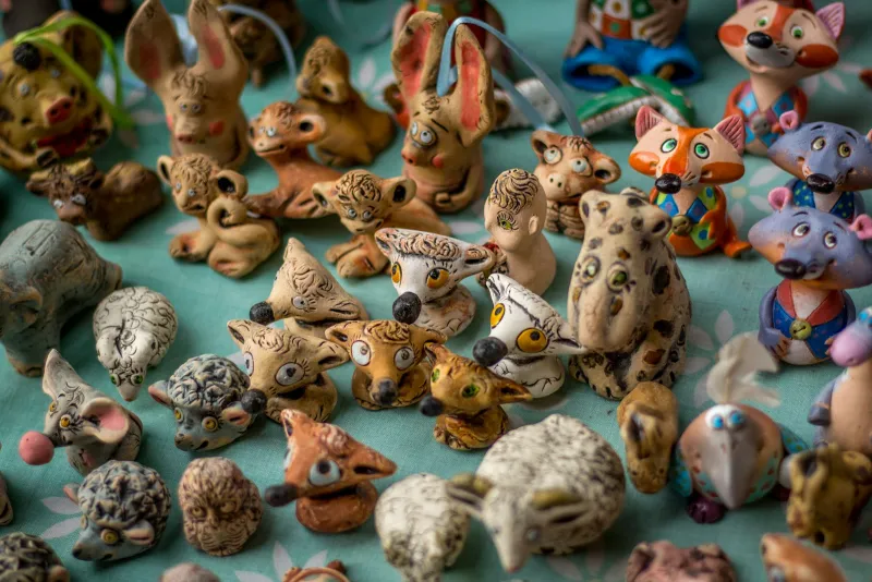 Rows of small hand-painted animal figurines on a tablecloth