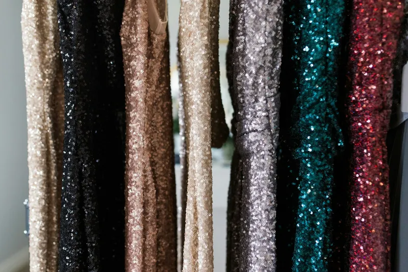 Gini London: independent womenswear, partywear and faux fur A row of sequin dresses in gold, black, silver, teal and red hanging on a rail