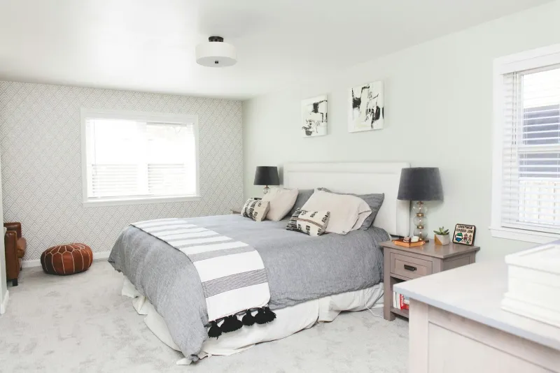 A calm grey and white bedroom with a made bed and bedside lamps