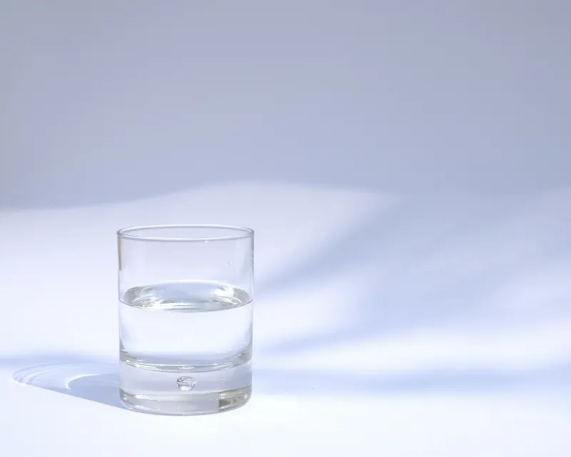 A clear glass of water on a white table in soft sunlight
