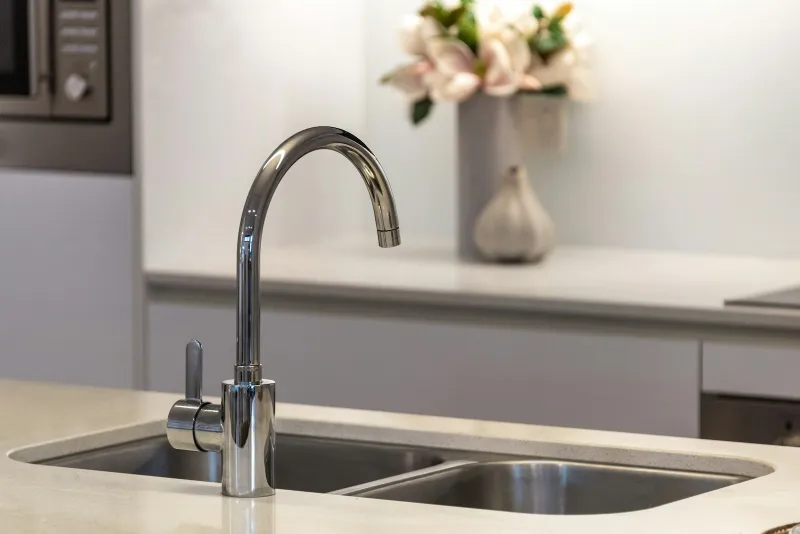 A chrome kitchen tap over a stainless steel double sink