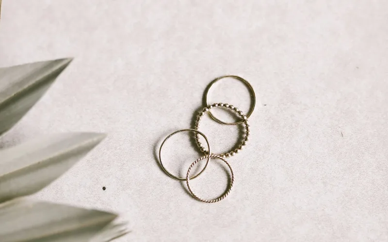 Hot Diamonds: sterling silver jewellery with a real diamond in every piece Four thin stacking rings on a pale stone surface beside dried palm leaves