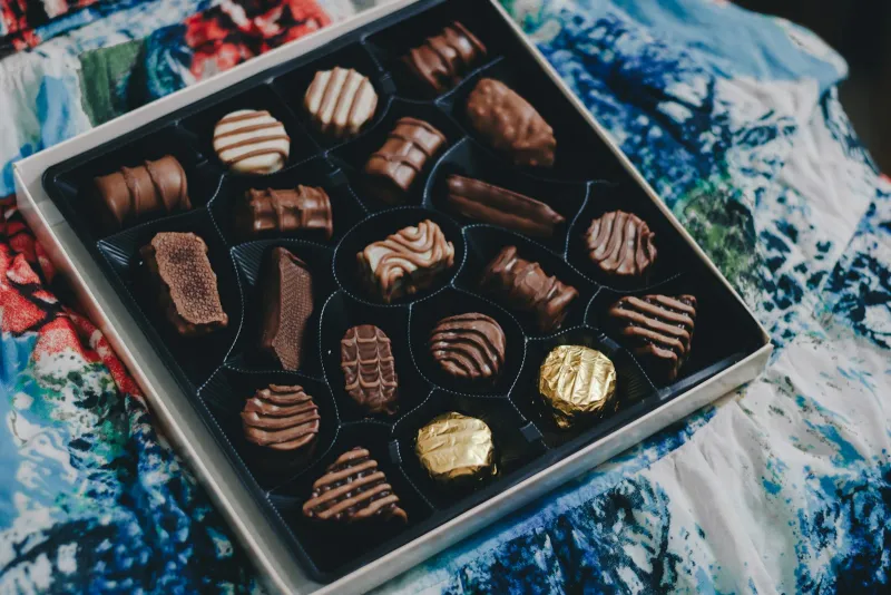 Open box of assorted chocolates on a patterned cloth