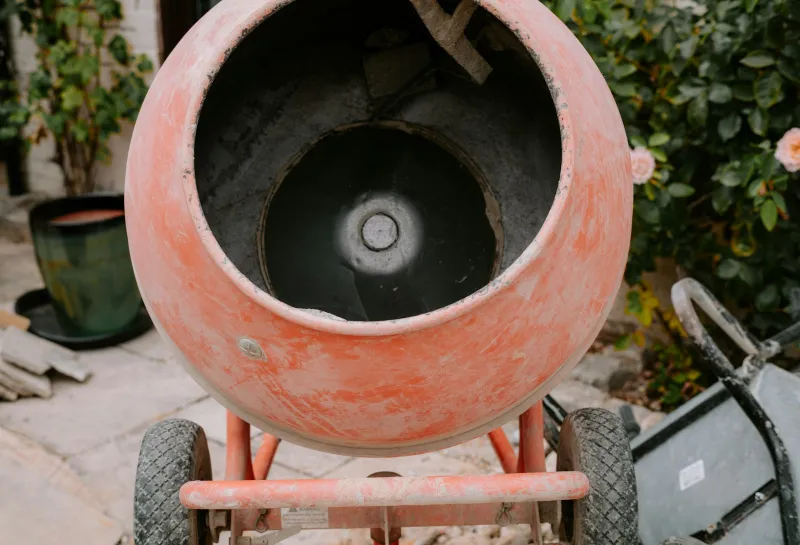 HSS DIY: hire the heavy kit and buy the materials in one basket An orange portable cement mixer on a garden patio next to a wheelbarrow