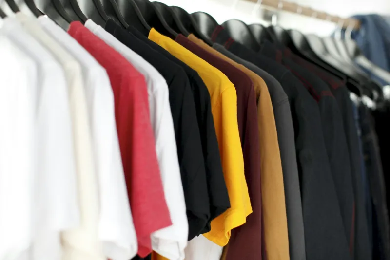 Row of coloured T-shirts and shirts hanging on a clothes rail