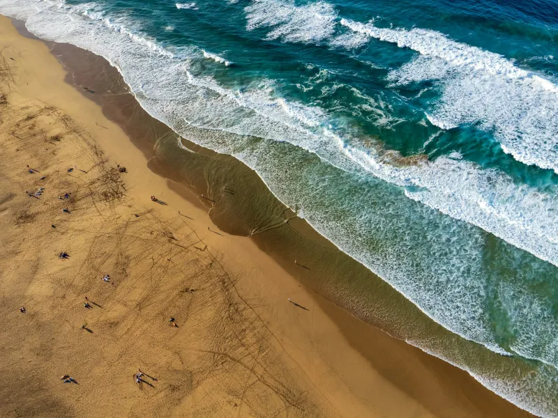 Aerial view of waves rolling onto a wide sandy beach in Fuerteventura