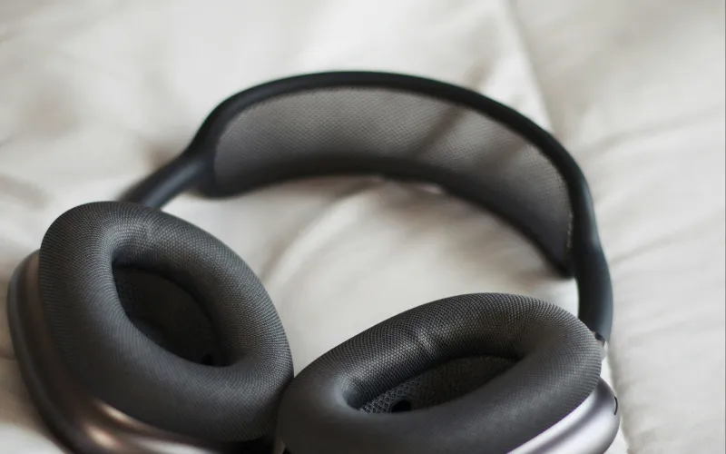 A pair of over-ear headphones lying on a white bed