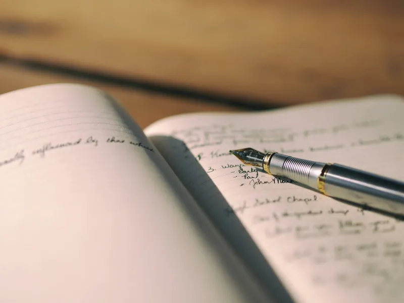 A fountain pen resting on an open notebook of handwritten notes