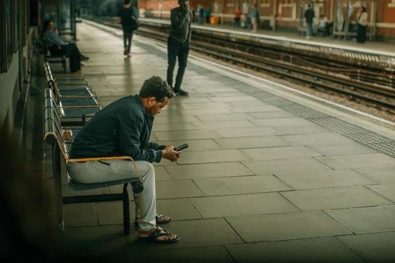 Lebara: cheap SIM only plans with international minutes included A man on a station platform bench checking his phone