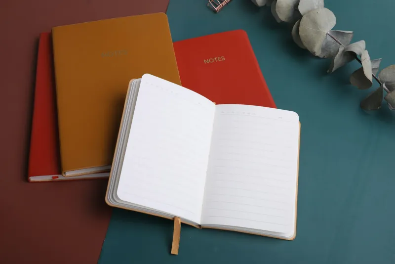 Lingzio: online language lessons from A1 to C2, with plans from $9.99 An open lined notebook beside two closed notebooks on a desk
