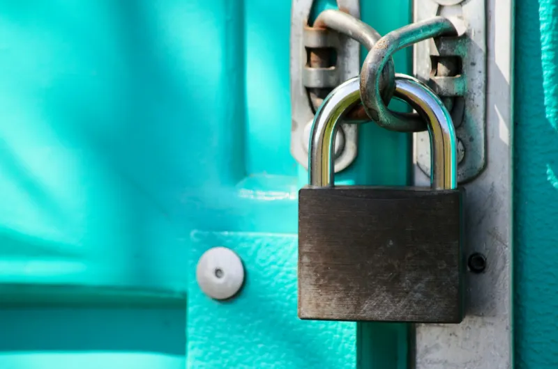 Close-up of a steel padlock on a turquoise door latch
