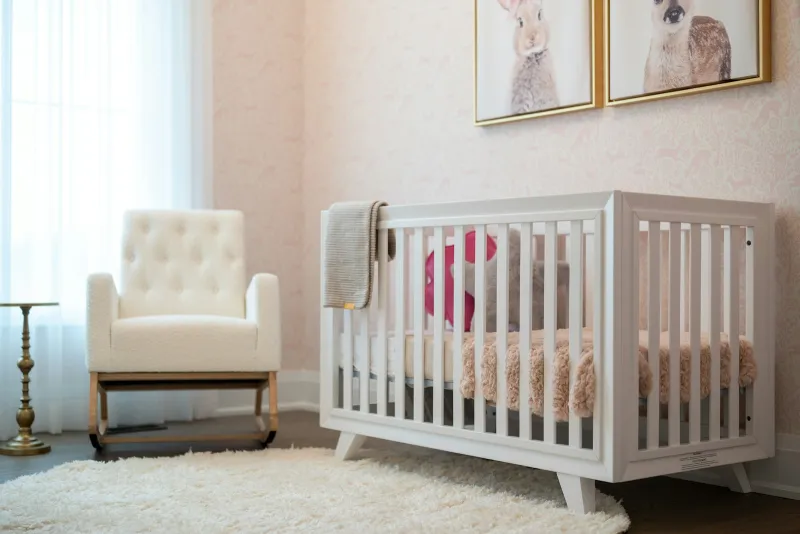 Nursery with a white cot, cream rocking chair and animal prints on the wall