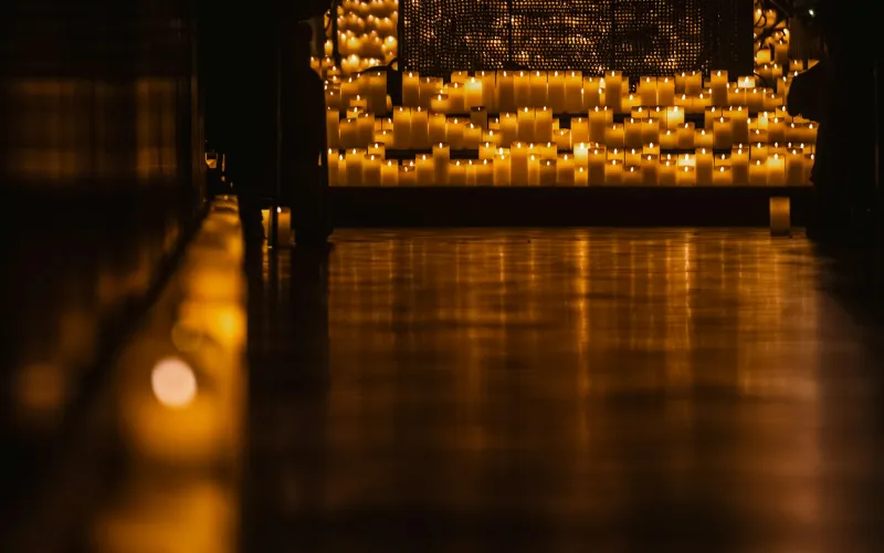 Rows of lit candles glowing in a dark room
