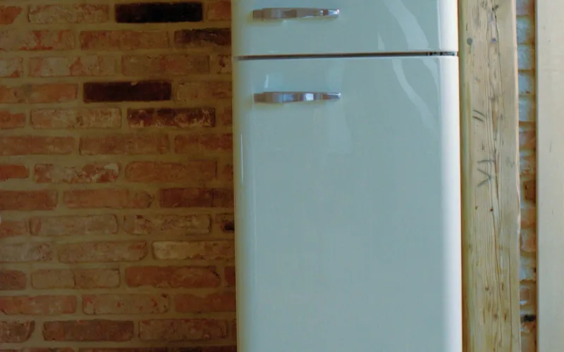 Retro-style cream fridge against an exposed brick wall