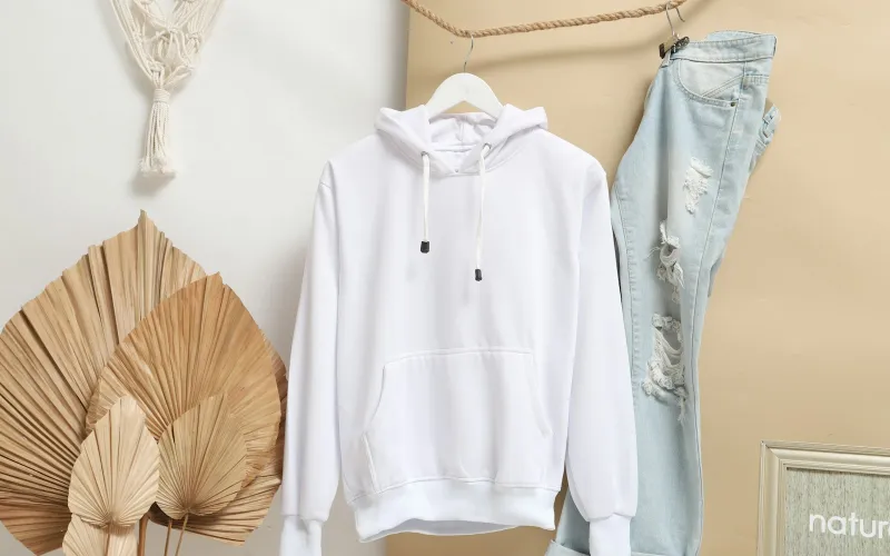 A plain white hoodie and ripped jeans hanging on a rope