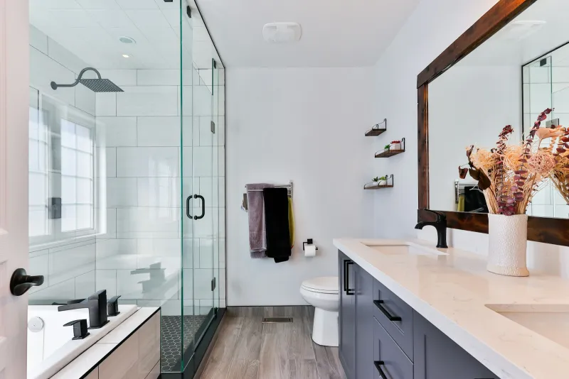 Bright modern bathroom with glass shower, toilet and double vanity