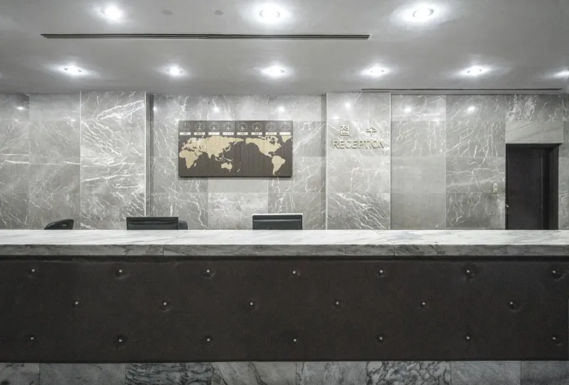 MYCO Works: virtual office addresses, call answering and meeting rooms An empty office reception desk in front of a marble wall with a world map