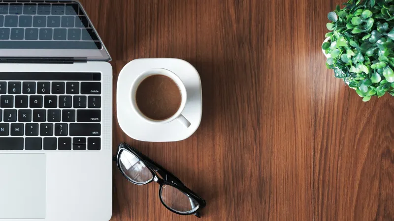 names.co.uk: a free .co.uk, cheap hosting and how to avoid renewal surprises A laptop, a cup of coffee, glasses and a small plant on a wooden desk