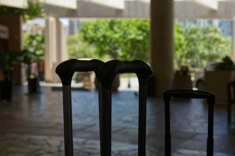 The extended handles of three suitcases standing in a bright hotel lobby