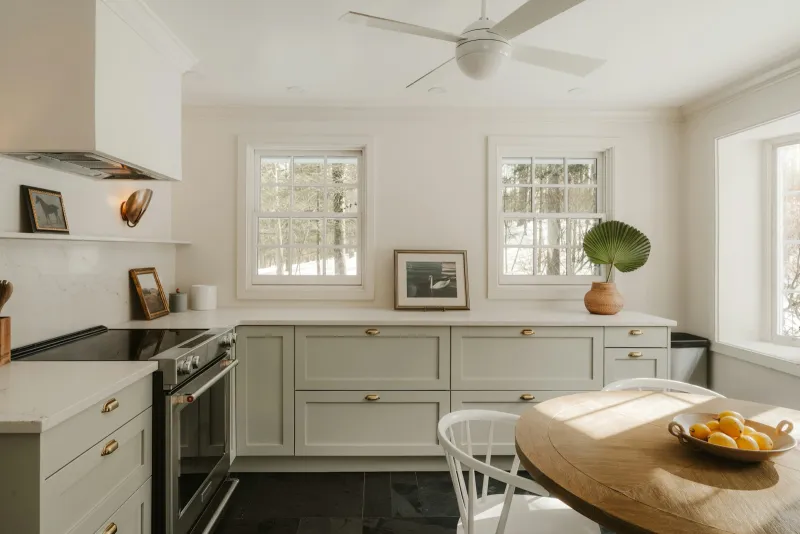 Bright kitchen with pale green cabinets and a bowl of lemons on a wooden table