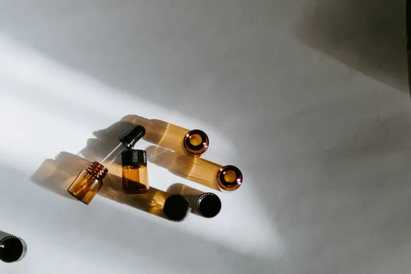 Small amber glass dropper bottles lying in sunlight on a white surface
