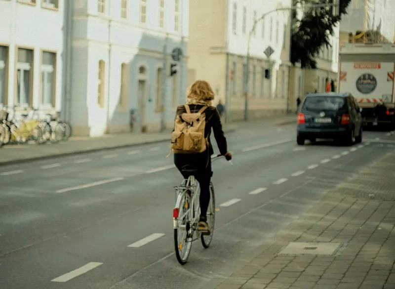 A cyclist with a backpack riding along a city street