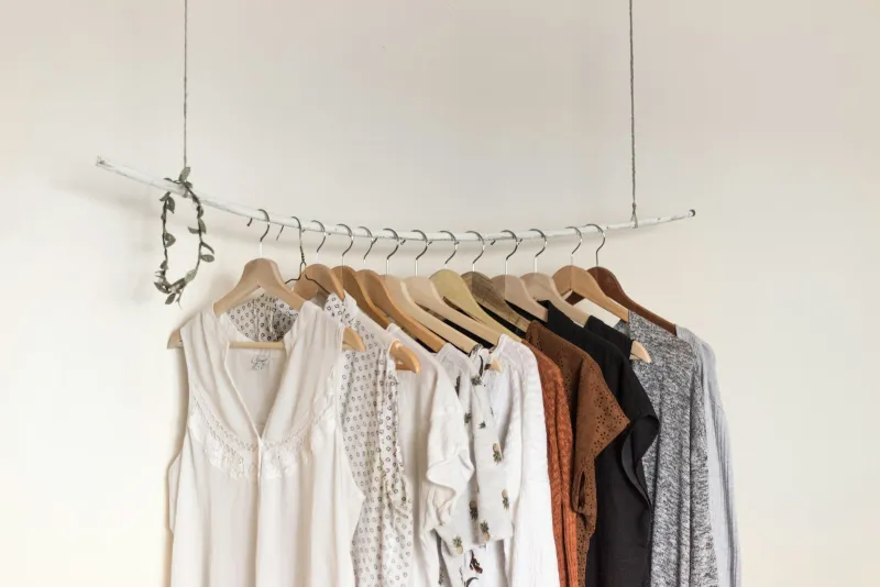 Tops and cardigans on wooden hangers on a simple clothes rail