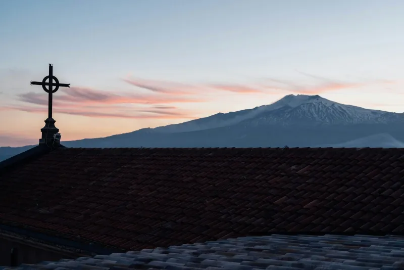 Rooftops at dusk near Taormina in Sicily with snow-capped Mount Etna behind