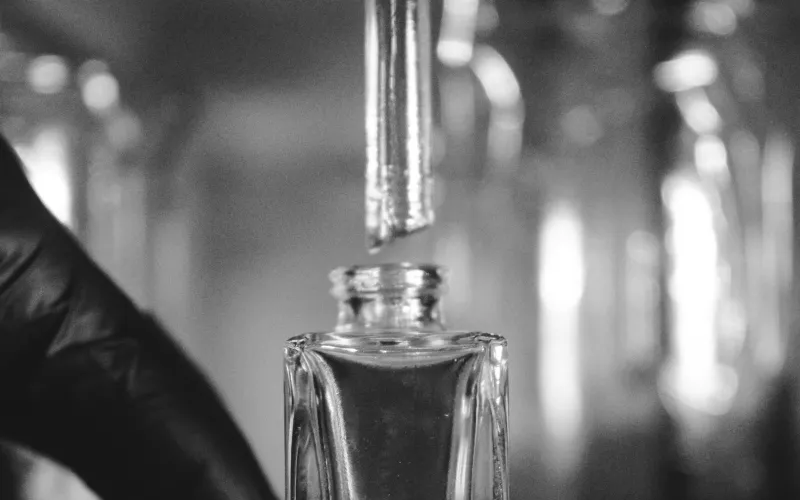 Nicchia Luxury: Italian niche perfumes, home scents and £5 samples A glass dropper releasing fragrance into a clear perfume bottle in a perfumer's workshop