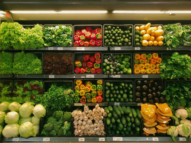 Shelves of fresh vegetables including peppers, courgettes and lettuce
