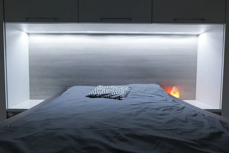 A double bed set into fitted over-bed cupboards with LED lighting