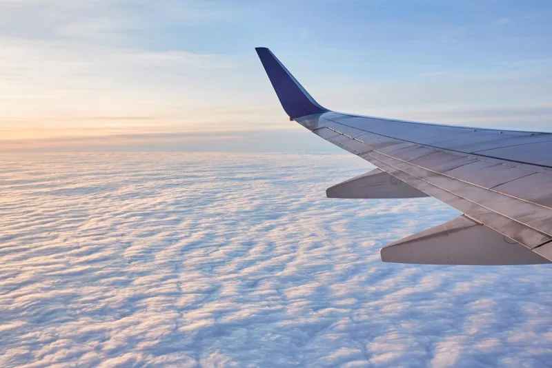 Aeroplane wing above a sea of clouds at sunrise