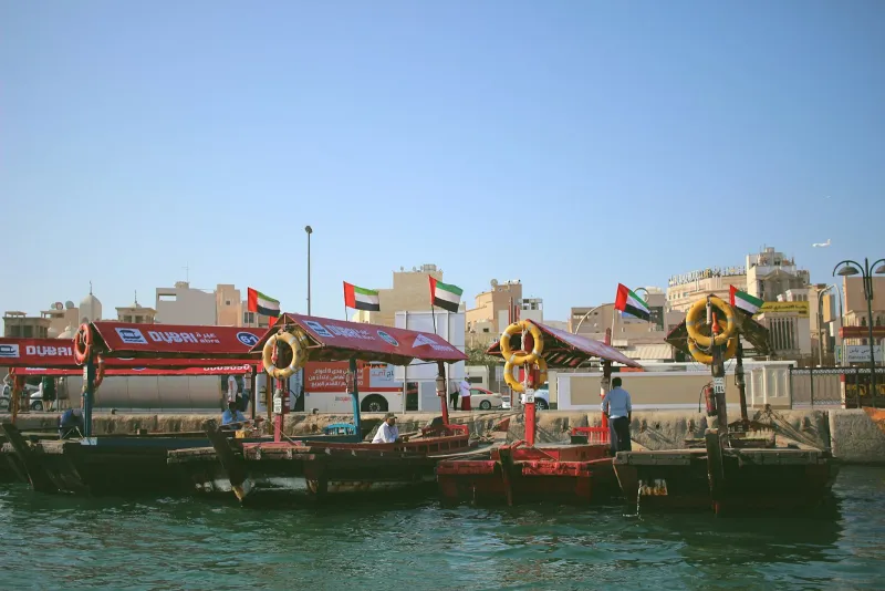 Traditional abra water taxis moored on Dubai Creek under a clear blue sky
