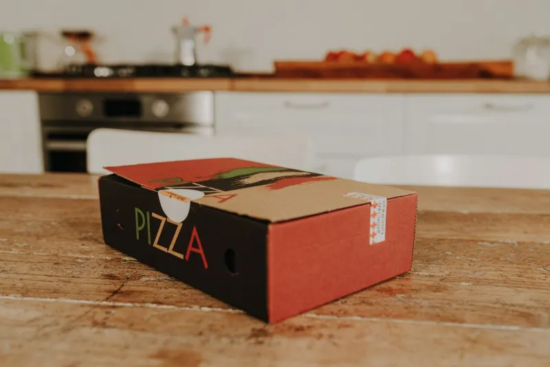 Takeaway pizza box on a wooden kitchen table