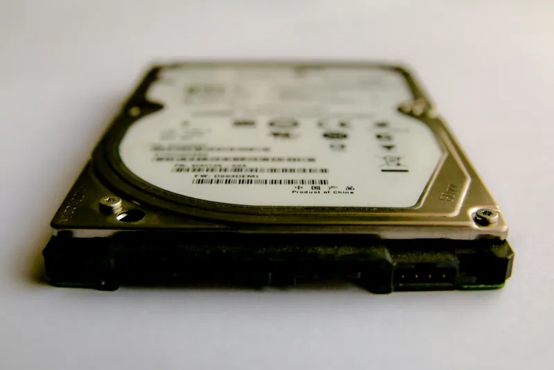 Close-up of a laptop hard disk drive lying flat on a pale surface